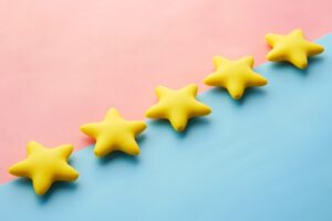 Cameo College Google Reviews - a row of yellow stars sitting on top of a blue and pink surface