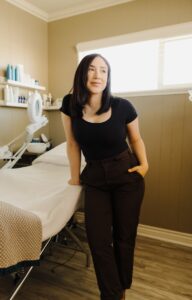 an Esthetician standing next to a bed in a room