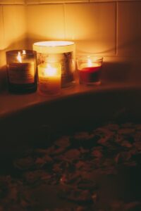 a bath tub filled with candles next to a tub filled with rocks