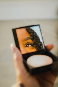 a woman holding a compact concealer makeup