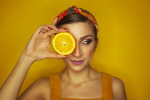 vitamin c - woman covering her right eye with orange slice