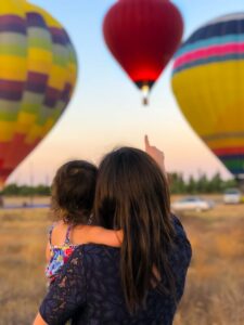Post Mother's Day beauty deals | woman carrying toddler point at hot air balloon