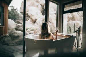 woman in white bathtub holding clear drinking glass | Home Day Spa