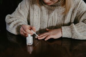 woman in gray sweater holding cigarette stick | Perfect At-Home Manicure