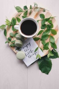 flat lay photography of leaves with cup of coffee and three macarons on chopping board | Practicing gratitude