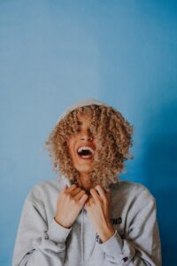 smiling woman wearing gray hoodie | Natural Curls