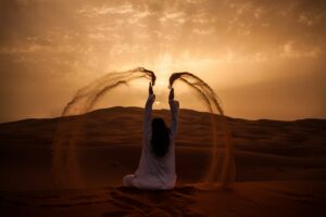 woman sitting on desert while playing sand during golden hour | Clean Makeup, Clean Beauty