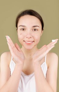 Teenager applying skincare cream showing confidence and natural beauty.