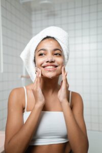 Smiling woman with face wash in a bathroom, embracing self-care and fresh skin.