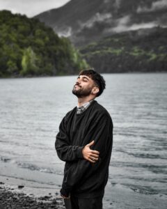 a man standing on a beach next to a body of water