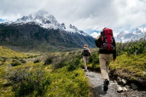 two person walking towards mountain covered with snow | Reduce Stress