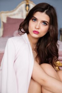 Close-up portrait of a stylish woman with glamorous makeup and pink lipstick, indoors.