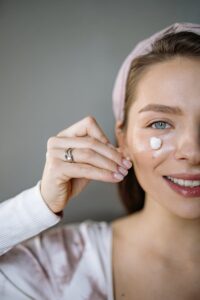 Close-up of a woman applying facial cream for skincare routine.