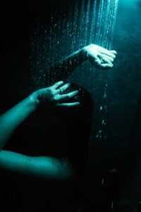 a woman's hand reaching for a shower head