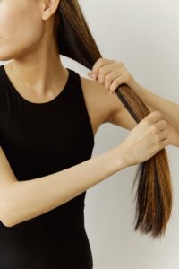 Close-up of a woman brushing her long hair in a simple indoor setting.