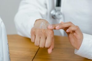 Close-up of a doctor applying lotion on their hand, focusing on skincare. Essential Skincare Routine