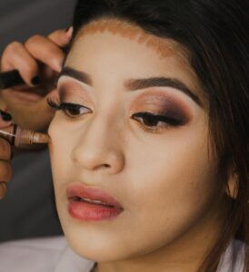 Detailed close-up of woman applying makeup, contouring forehead.