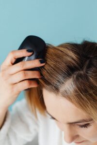 Close-up of woman brushing her hair, focusing on groomed fingernails and haircare routine.