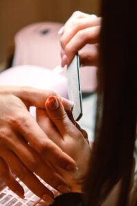 Close-up of a professional manicure session with a nail file used by a beautician.