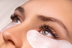 Eyelash Extension Procedure. Close up view of beautiful female eye with long eyelashes, smooth healthy skin