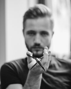 shallow focus photo of man holding scissors | Learn Hair Cutting Techniques