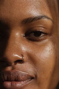 A detailed close-up of a woman's face highlighting her skin texture and nose ring. | Products for oily skin