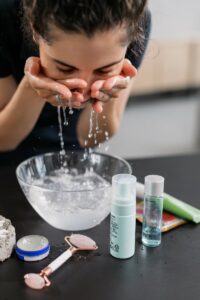 A woman practicing her skincare routine with a face wash and products on a counter.