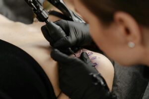 Tattoo artist creating intricate design on client in studio close-up view.