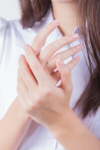 woman in white shirt covering her face with her hand | Healthy Nails