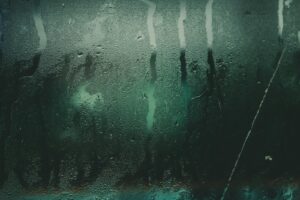 Close-up of a moist glass surface with water droplets and streaks creating an abstract texture.