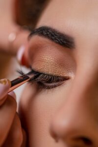 a woman getting her make up done with a brush | Lash Extensions