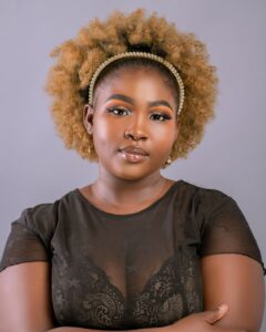 Portrait of a woman with afro hairstyle, wearing makeup and a black top.