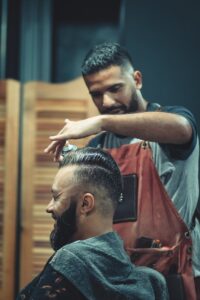 Skilled barber styling a man's hair in a modern barbershop setting, creating a trendy look. | Become a Licensed Barber