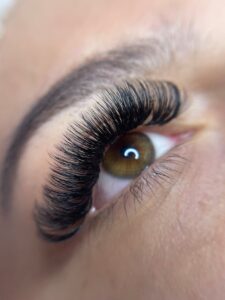 Detailed close-up of a woman's eye with styled eyelashes and groomed eyebrow. | Russian Volume Lash Extension