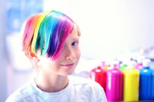 A cheerful child with vibrant rainbow-dyed hair, symbolizing diversity and individuality.