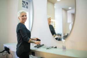 A hair stylist in a modern salon in Portugal with tools and a mirror.