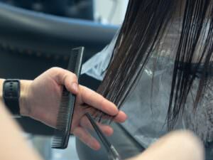 Blowout Styling Tips: 6 Techniques for Salon-Quality Results 2 Close-up of a professional haircut in progress at a salon, highlighting comb and scissors.