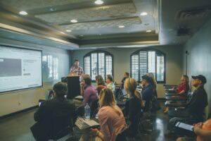 a group of people in a room with a projector screen | 