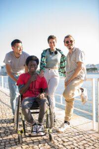 A diverse group of young friends share laughter by the riverside, highlighting friendship and inclusivity.